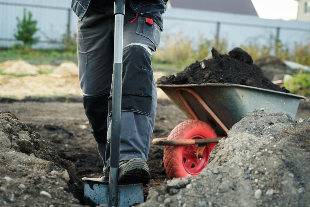 praca-z-lopata-i-taczka-narzedzi-ogrodniczych-na-terenie-przygotowan-wiejskiego-domu-min
